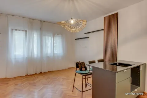 Small kitchen with an island and bar stools in the living area. - image 2