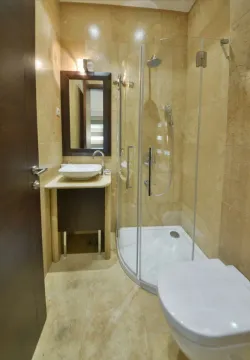 Kompaktno kupatilo obloženo bež pločicama sa tuš kabinom, umivaonikom i wc šoljom. - image 15