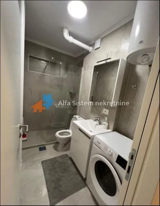 Modernly equipped bathroom with a walk-in shower and a washing machine.