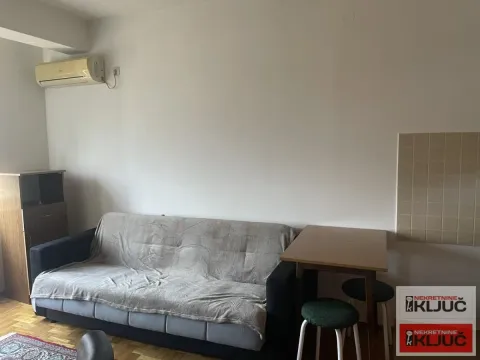 Dnevna soba sa kaučem, trpezarijskim stolom i klima uređajem na zidu. - image 3