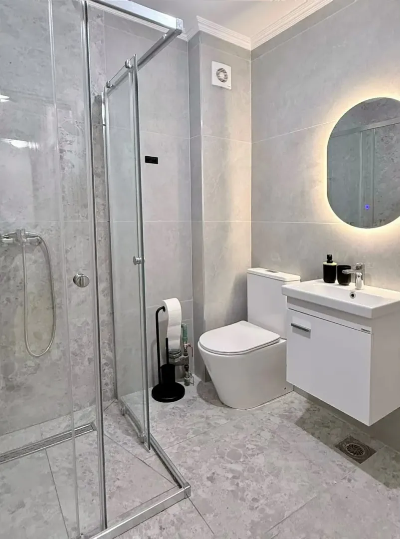 Modernly equipped bathroom with a walk-in shower and light tiles.