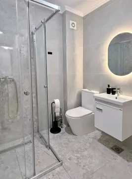 Modernly equipped bathroom with a walk-in shower and light tiles. - image 6