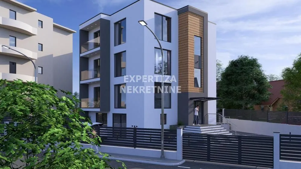 Exterior view of a modern residential building with a courtyard and fence.