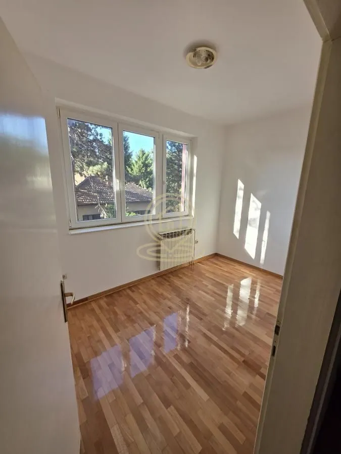Empty room with hardwood floors and a window overlooking the courtyard.