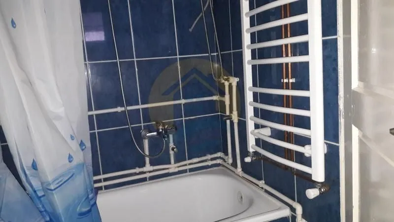 Bathroom with a bathtub and a white radiator against blue tiles.