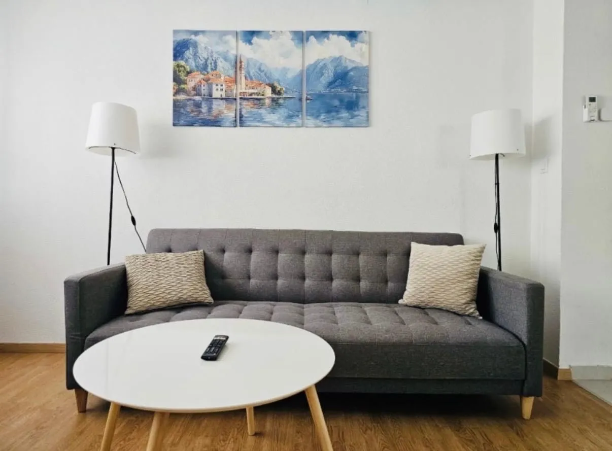 Dnevna soba sa sivim trosjedom, bijelim stočićem i dvije podne lampe.