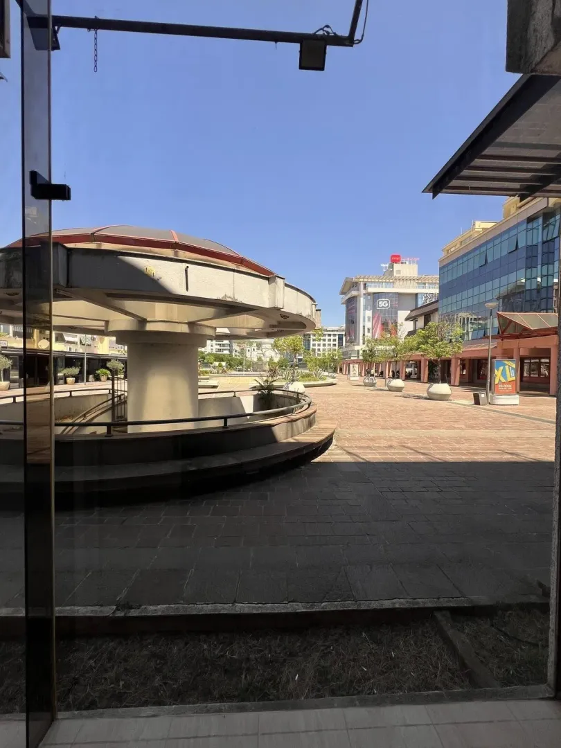 View through a glass door onto a public square and surrounding commercial buildings.
