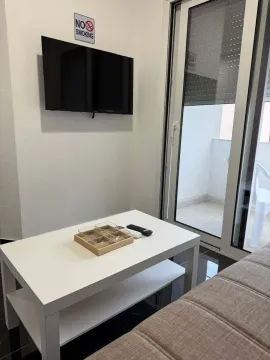 Living room with a sofa, coffee table, TV, and access to the terrace. - image 3