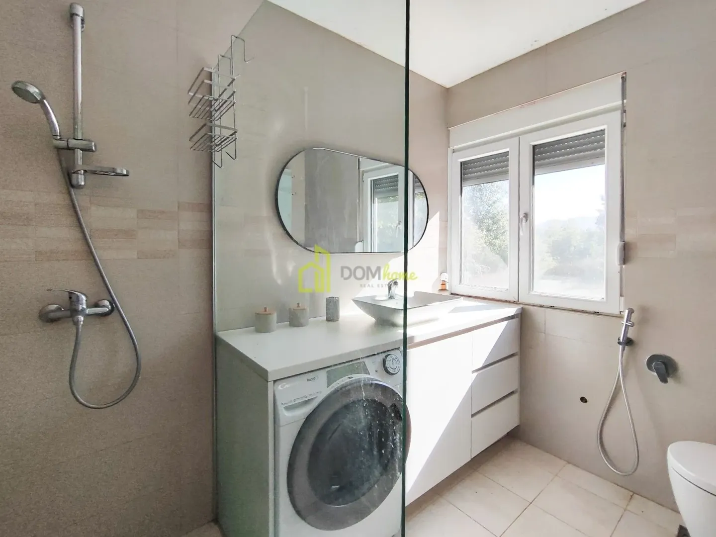 Modern bathroom equipped with a walk-in shower, washbasin, and washing machine.