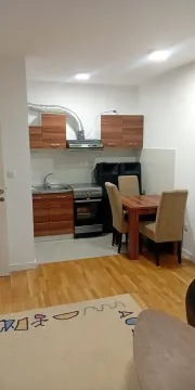 Manja kuhinja sa trpezarijskim stolom i drvenim elementima. - image 3