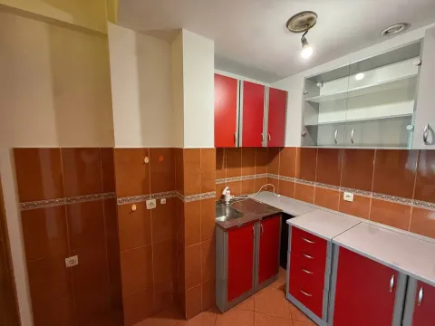 Kitchen with red cabinets and brown ceramic tiles. - image 4