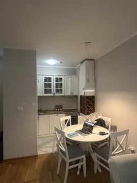 Bright dining area with a round table and a small kitchen in the background. - image 3