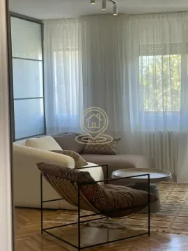 Dnevna soba sa garniturom, foteljom i velikim prozorima sa zavesama. - image 2