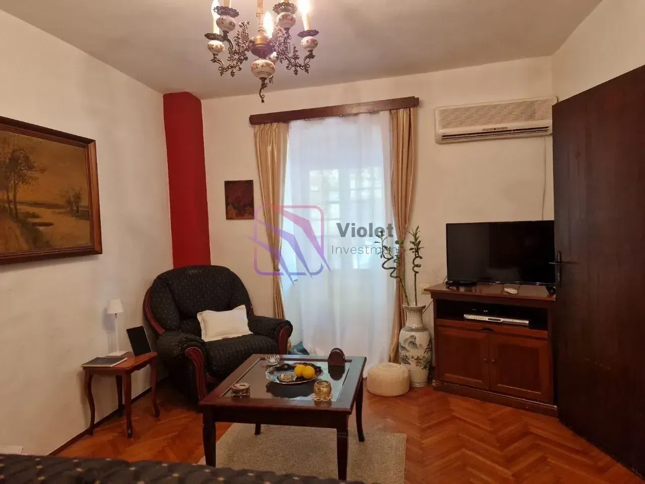 Dnevna soba sa foteljom, stočićem za kafu i televizorom.