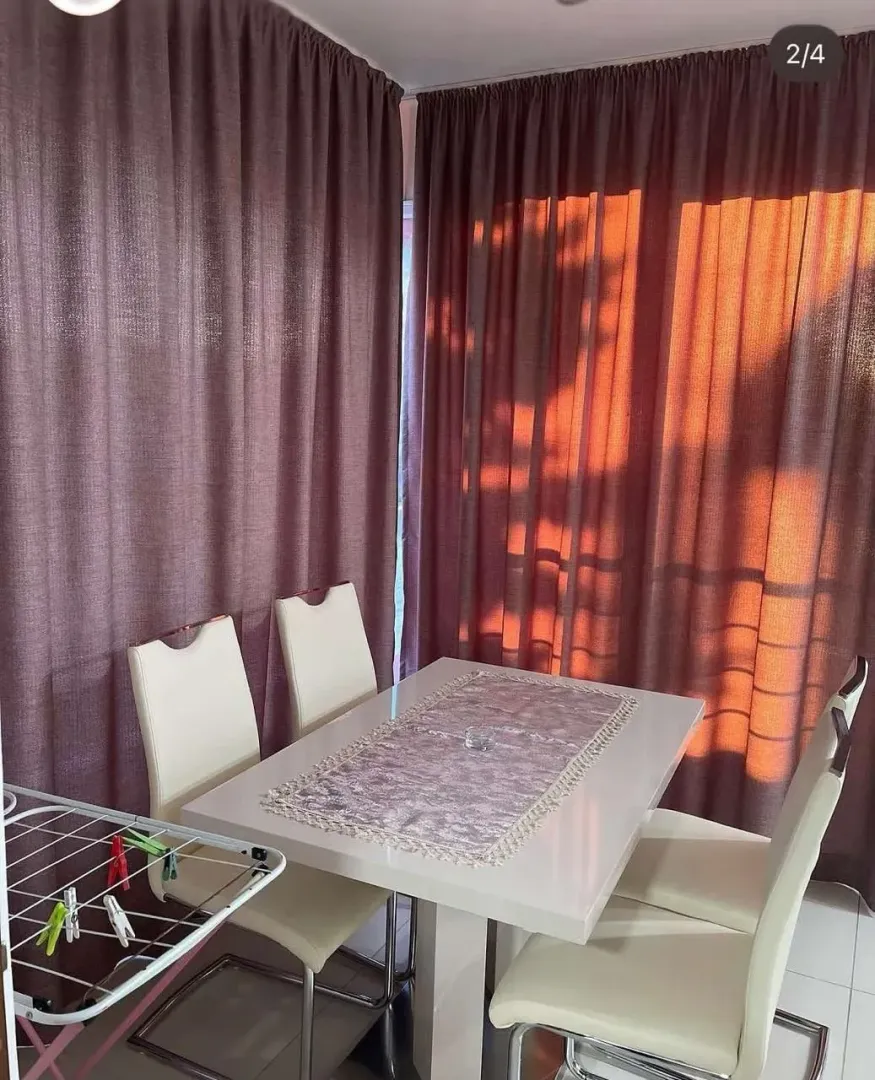 Dining room with a table, chairs, and curtains on the windows.