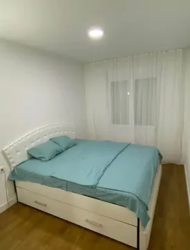 Bedroom with a double bed and a window with white curtains. - image 2
