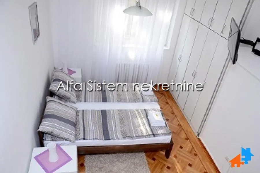 Bedroom with two single beds, a large wardrobe, and wooden flooring.