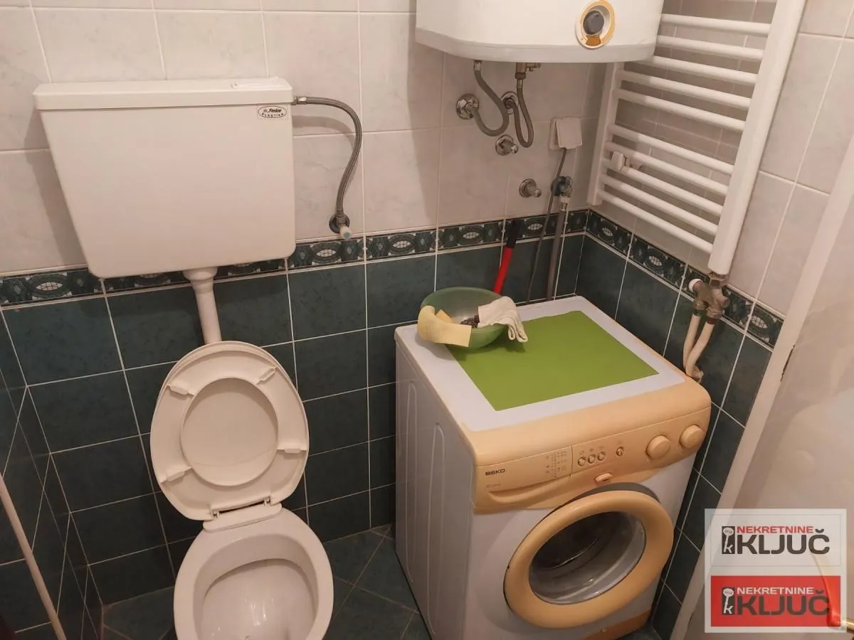 Manje kupatilo sa toaletom, veš mašinom i bojlerom.