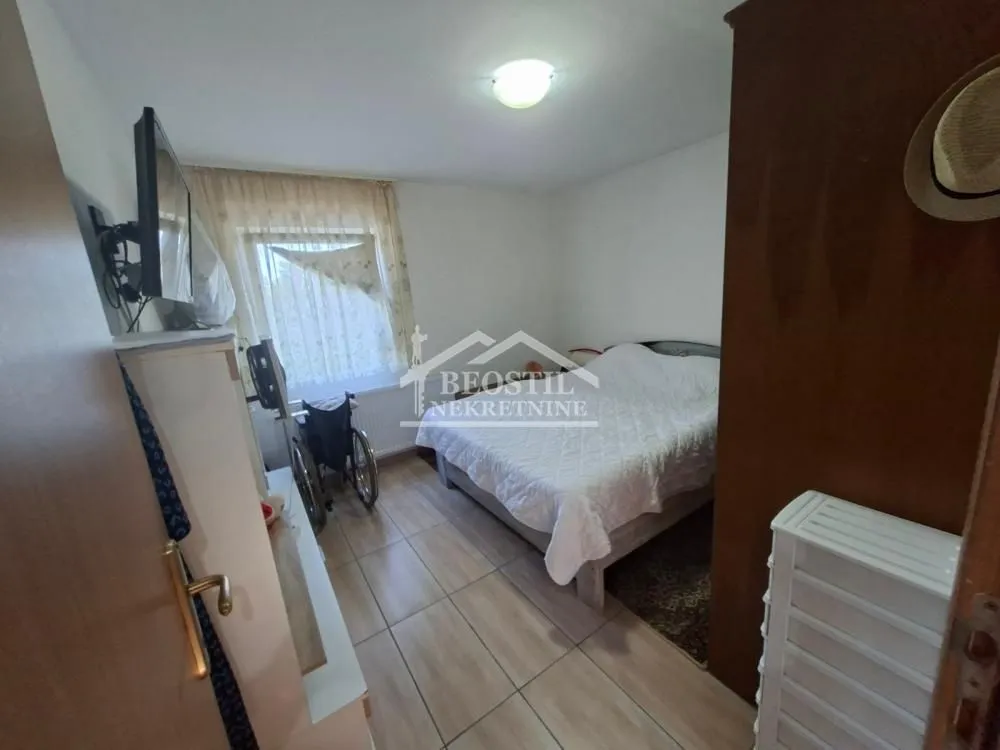 Manja spavaća soba sa bračnim krevetom, ormarom i prozorom.