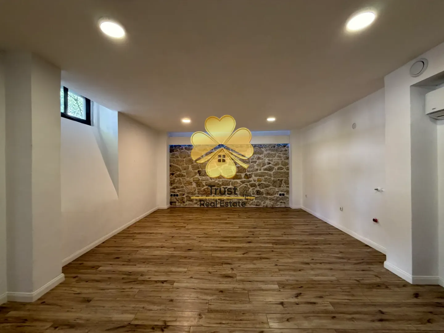 Empty room with wooden flooring and a stone accent wall.