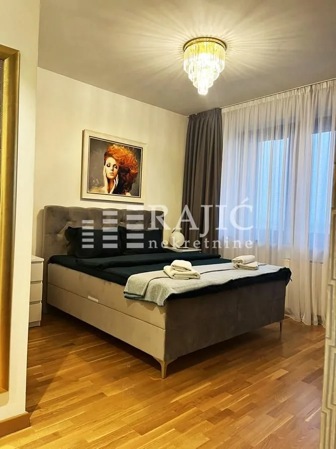 A furnished bedroom with a double bed and wooden flooring.