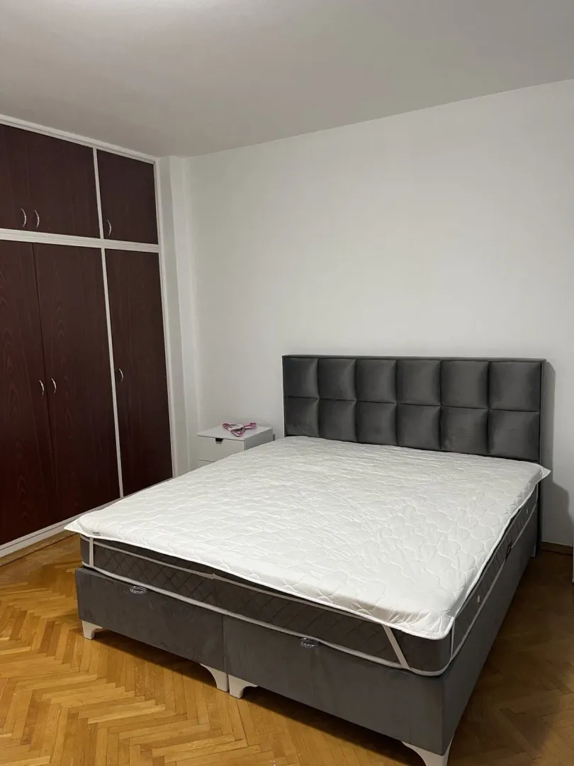 Jednostavna spavaća soba sa velikim bračnim krevetom i ugradnim ormarom.