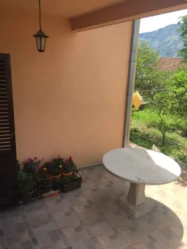 Natkrivena terasa sa kamenim stolom i pogledom na dvorište. - image 7