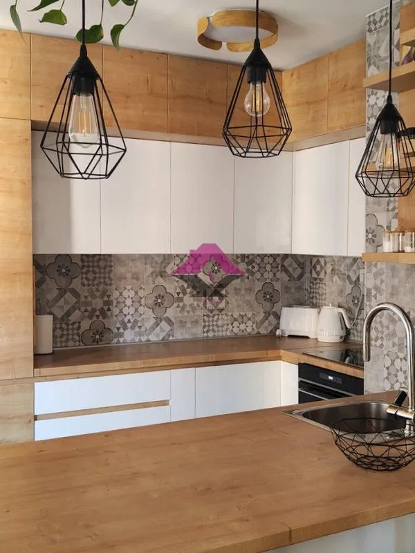 Modern kitchen with wooden elements, white cabinets and decorative tiles.