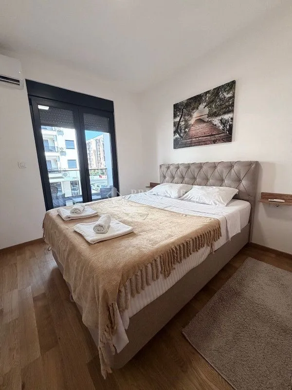 Furnished bedroom with a large double bed and balcony doors.