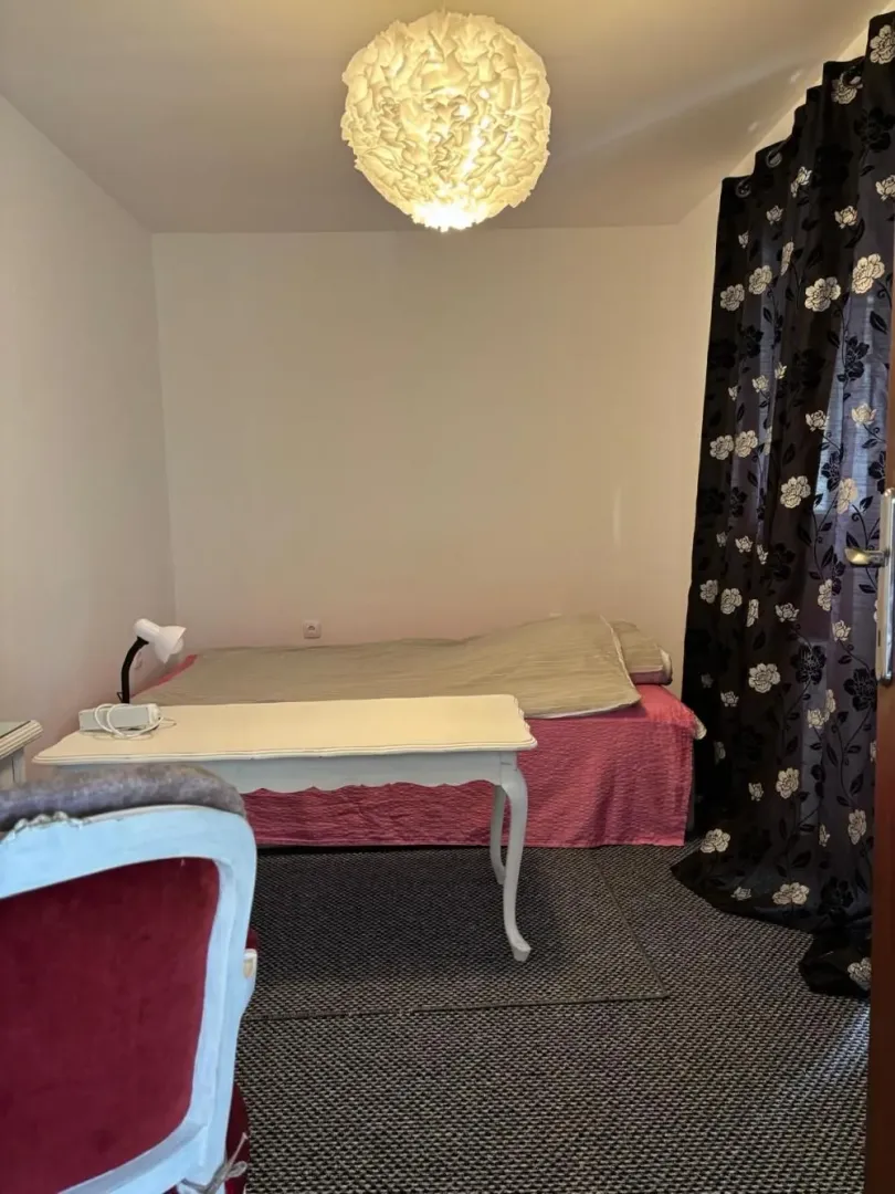 Manja spavaća soba sa krevetom, stolom i lusterom.