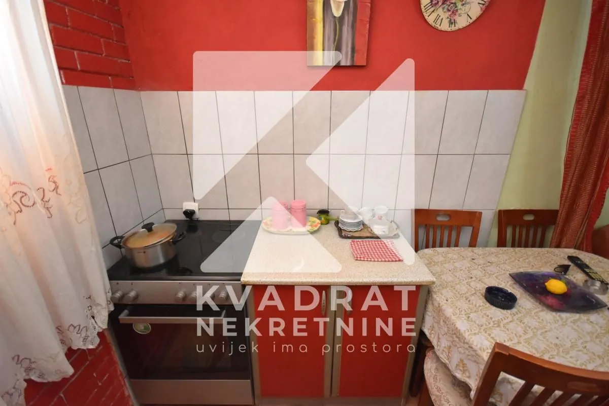 Kuhinja sa šporetom i trpezarijskim stolom.