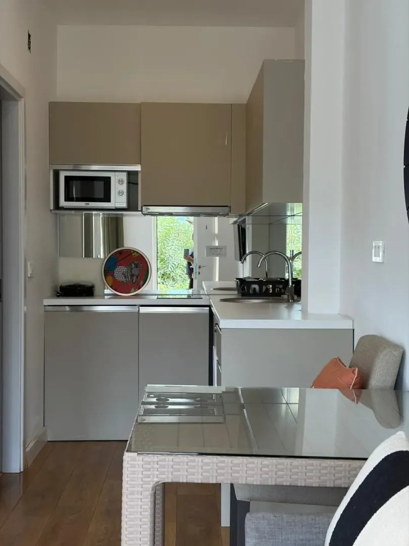 Small modern kitchen with a dining table and built-in units in light tones.