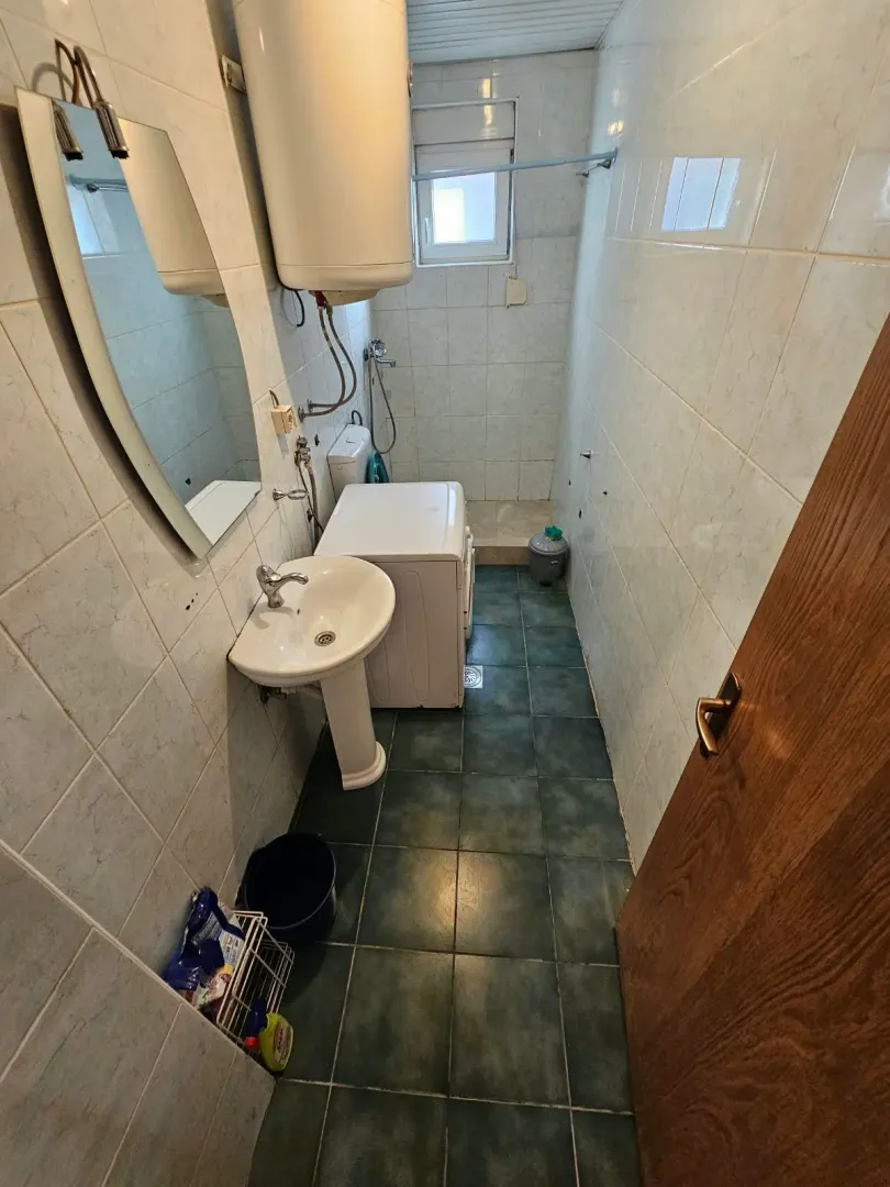 Prikaz kupatila sa umivaonikom, bojlerom i tuš kabinom.