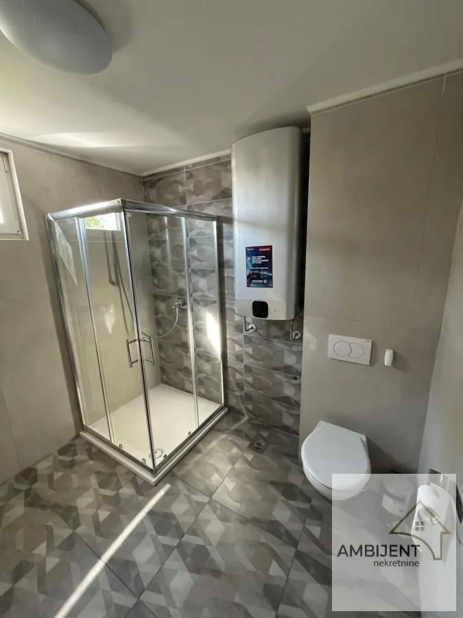 Bathroom with a shower cabin, toilet, and water heater.
