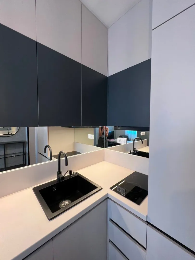 Modern kitchen with a sink, built-in cooktop, and a wall mirror.