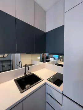 Modern kitchen with a sink, built-in cooktop, and a wall mirror. - image 6