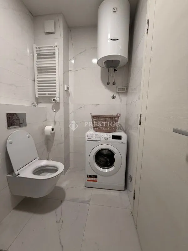 Modern bathroom equipped with sanitary ware, water heater, and washing machine.