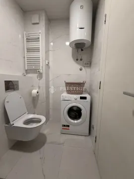 Modern bathroom equipped with sanitary ware, water heater, and washing machine. - image 9