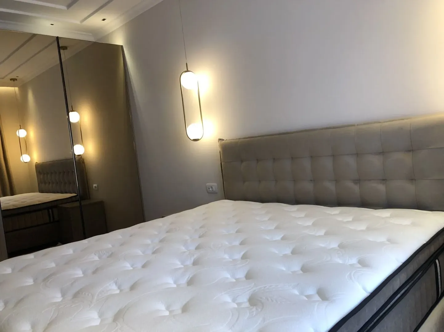 Bright bedroom featuring a large bed and a built-in wardrobe with mirror doors.