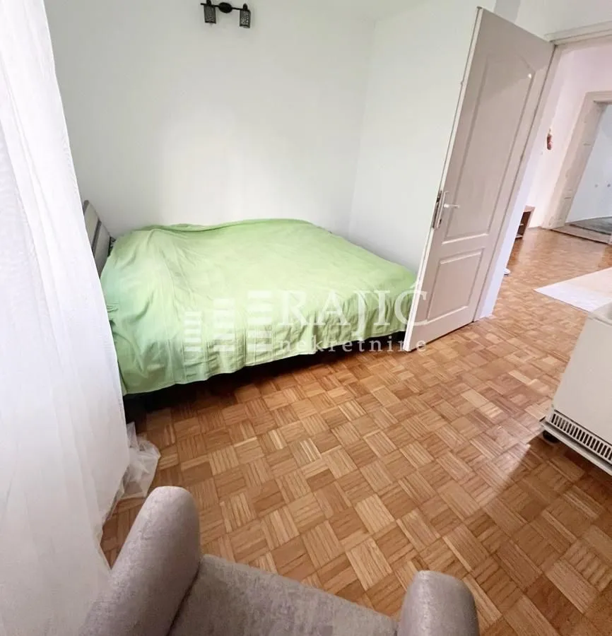 Furnished bedroom with a double bed and parquet flooring.