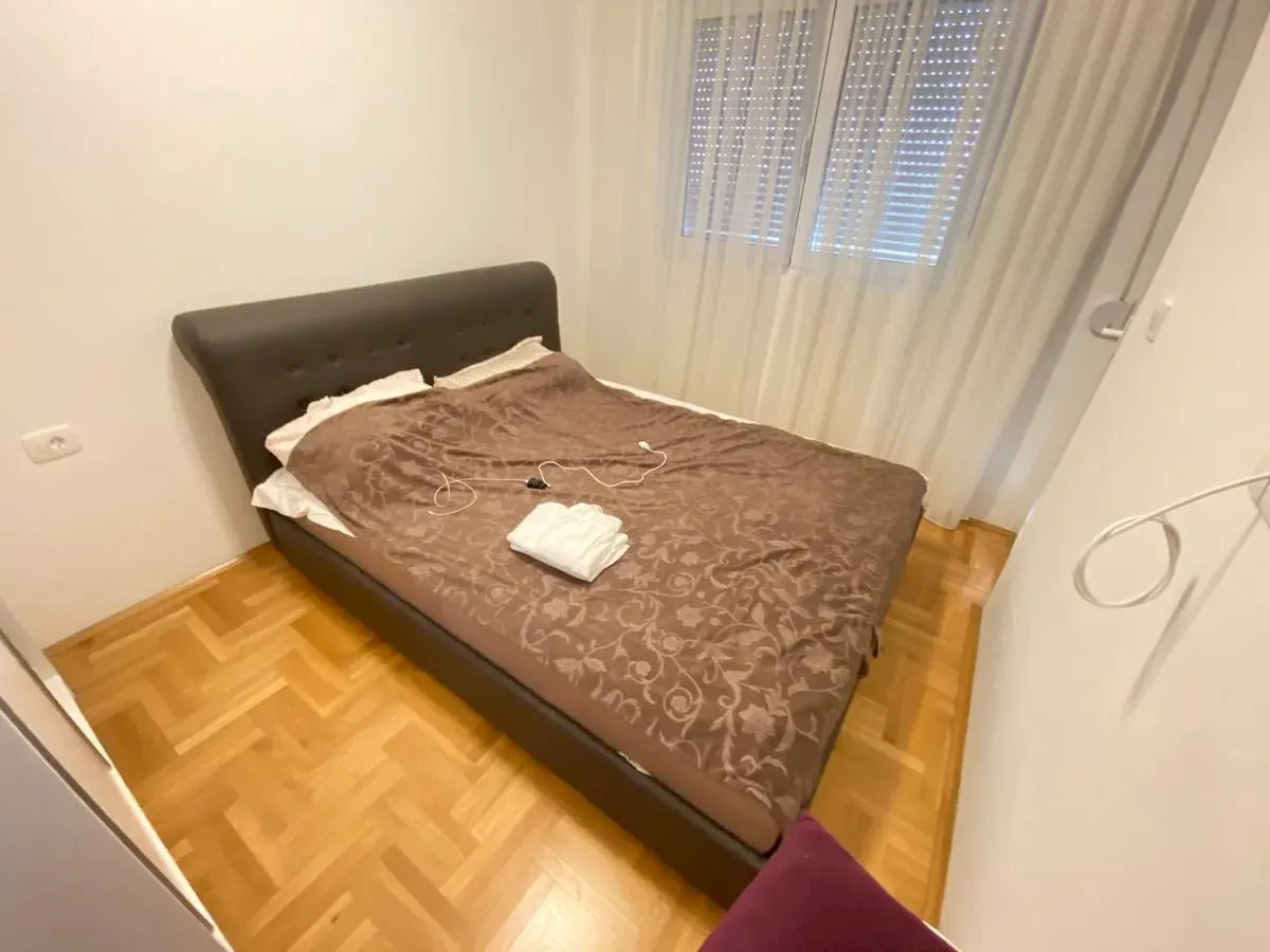 Manja spavaća soba sa bračnim krevetom i parketom na podu.