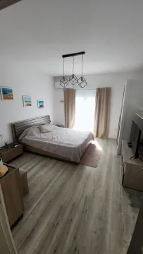 Spavaća soba sa bračnim krevetom, drvenim namještajem i TV-om. - image 9