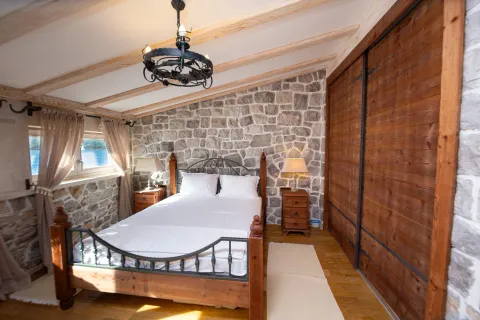 Bedroom with a double bed, stone wall, and wooden beamed ceiling. - image 11