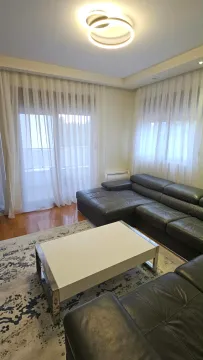 Dnevna soba sa garniturom, klub stolom i prozorima sa bijelim zavjesama. - image 4