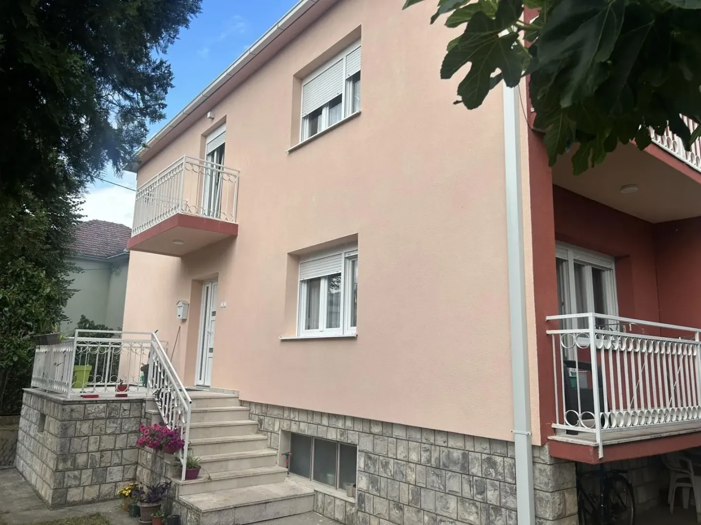 Facade of a two-story house with exterior stairs and balconies.