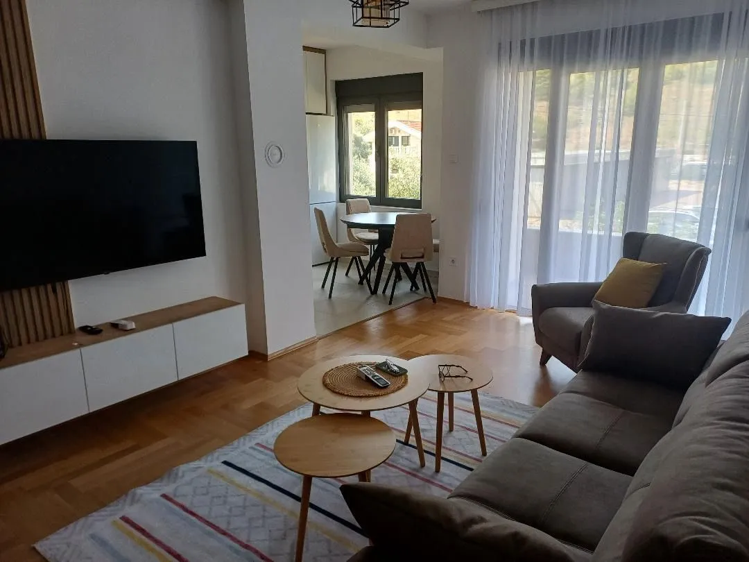 Spacious living room with a sofa, TV, and dining area in the background.