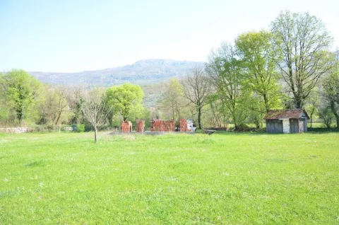 Prostran zeleni plac sa građevinskim materijalom i malom pomoćnom kućicom. - image 5