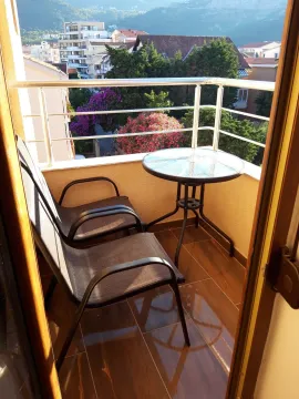 Furnished balcony with a table and two chairs and a view of the neighborhood. - image 7