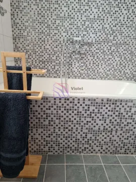 Bathroom with a bathtub and mosaic wall tiles. - image 9