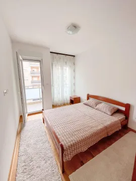 Svijetla spavaća soba sa drvenim krevetom i izlazom na balkon. - image 5